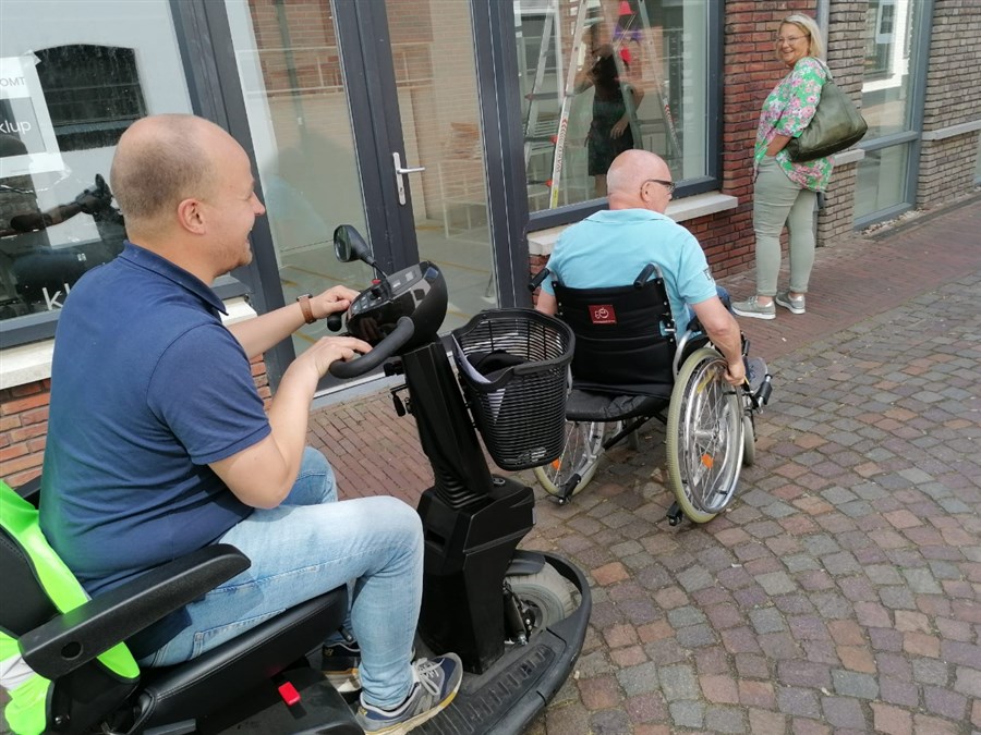 Mensen in een scootmobiel en rolstoel rijden elkaar in de weg
